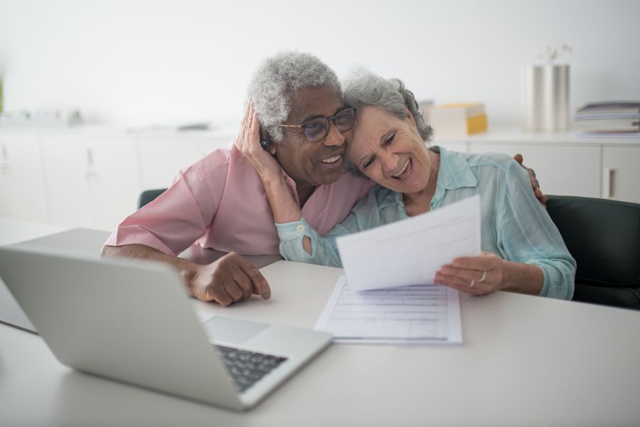 Casal de idosos sorrindo enquanto revisa documentos