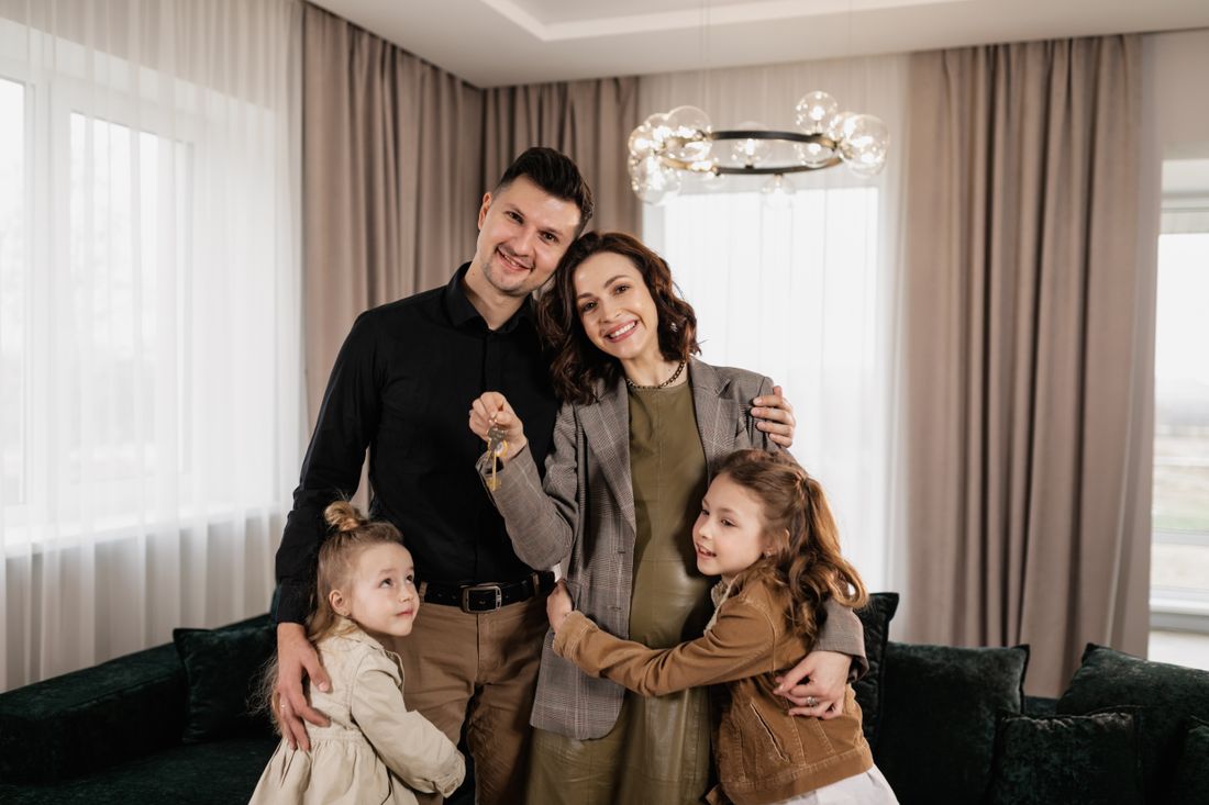 Família sorrindo na sala de casa, segurando as chaves